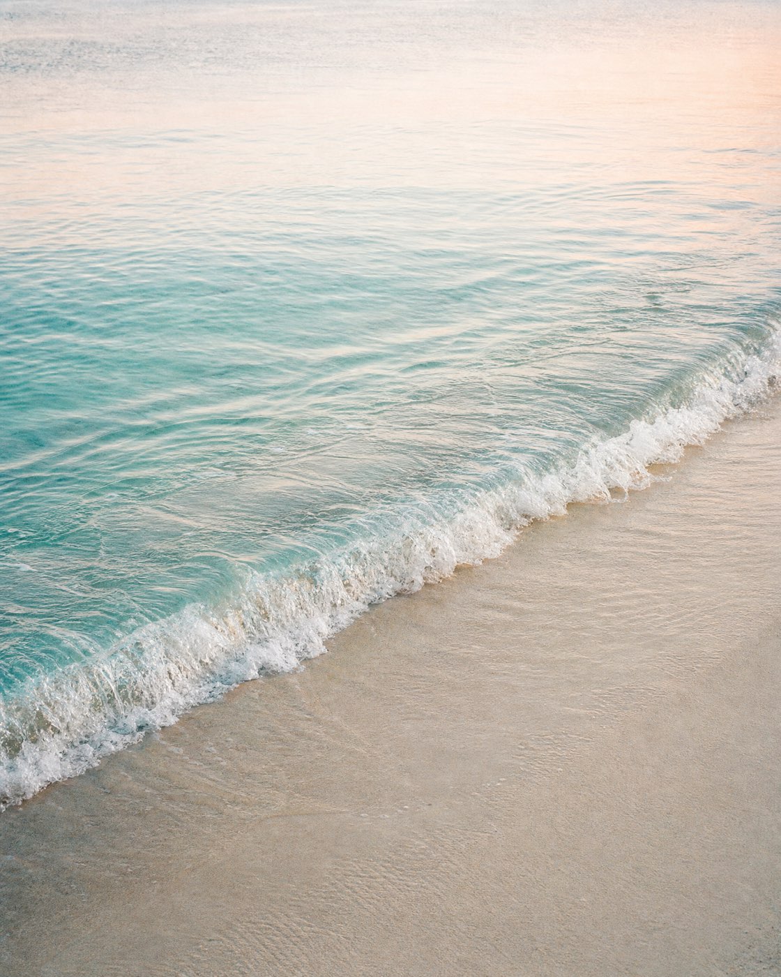 Turquoise water arriving at a calm sandy beach